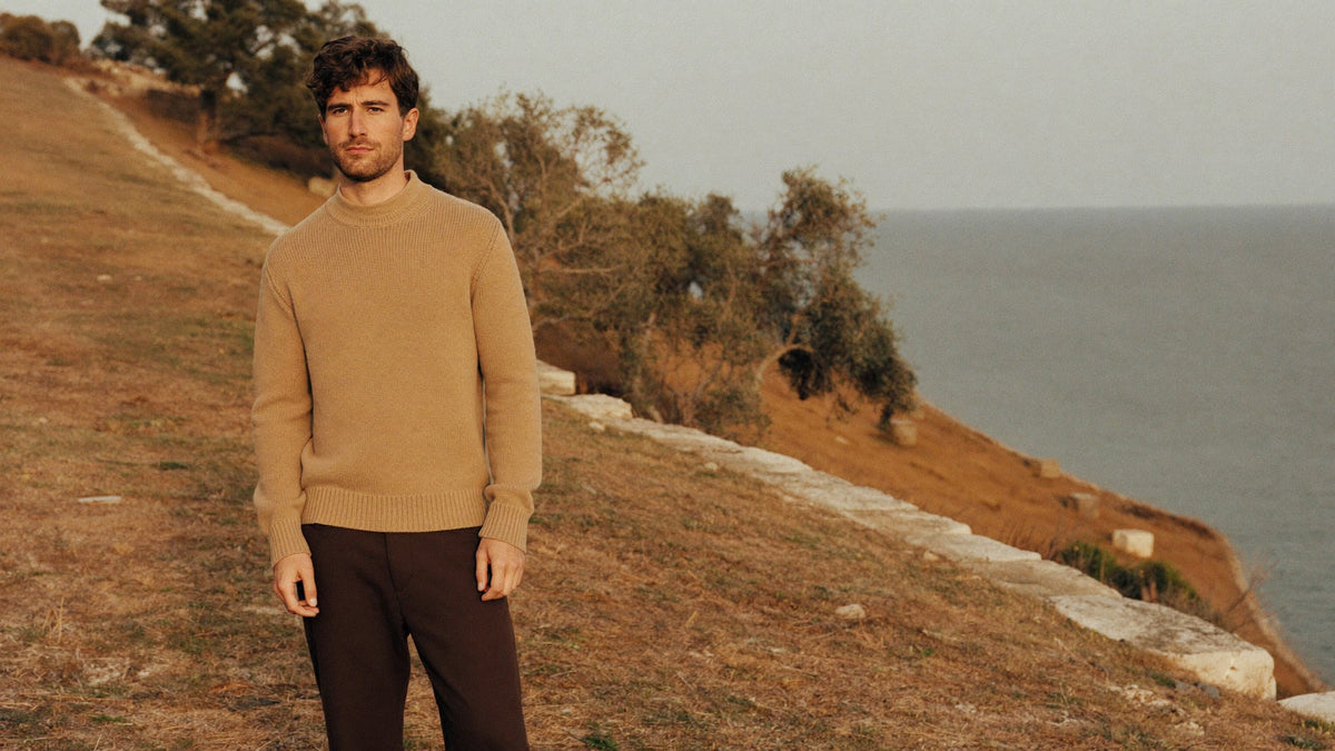 Delmont autumn, man in a camel knit sweater on a coastal cliff path above the sea